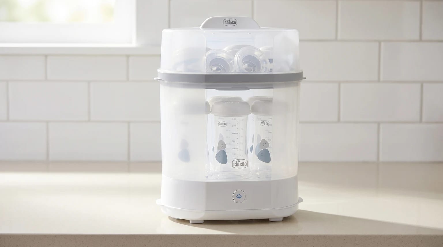 Esterilizador elétrico de biberões da Chicco numa bancada de cozinha clara e moderna, banhada por luz natural suave.