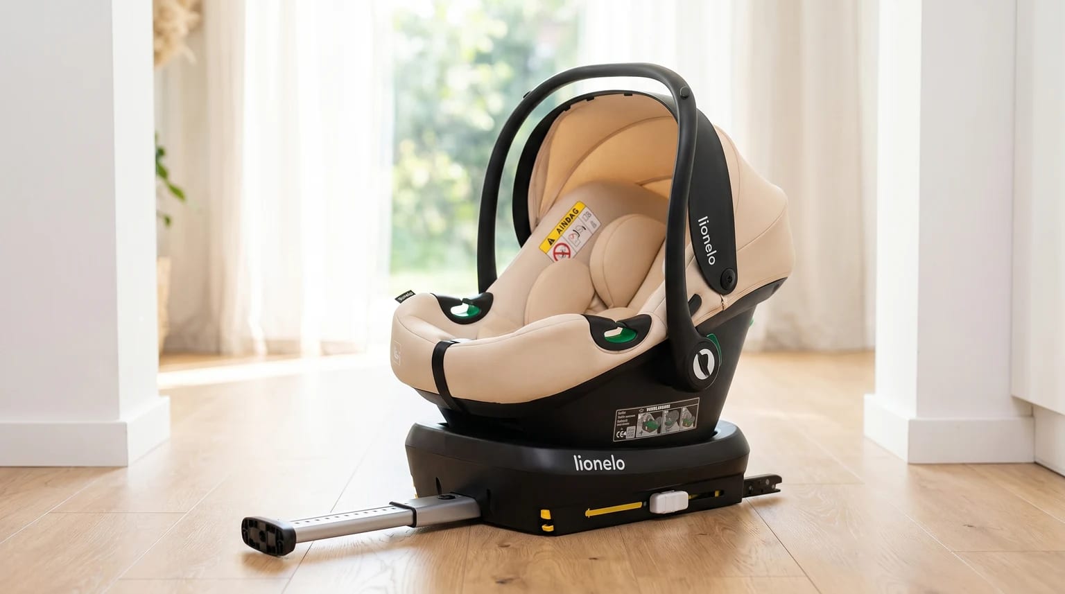 Cadeira auto para bebé Lionelo Astrid i-Size, em bege e preto com base ISOFIX, pousada num chão de madeira clara numa casa moderna e luminosa.