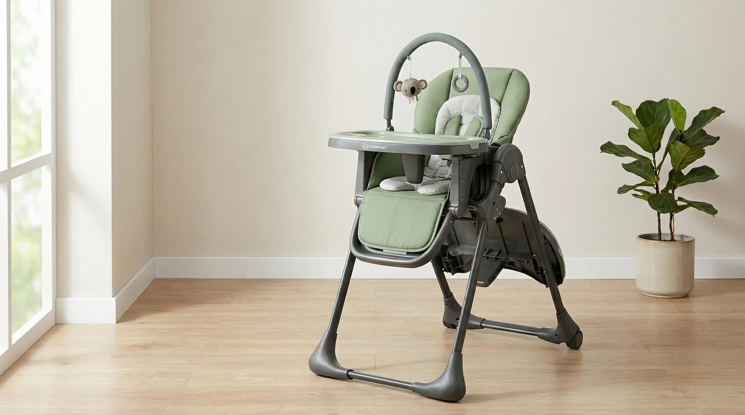 Cadeira de papa Kinderkraft TUMMIE verde e cinza, com arco de brincar, num ambiente de sala de jantar moderno e luminoso com chão de madeira clara.