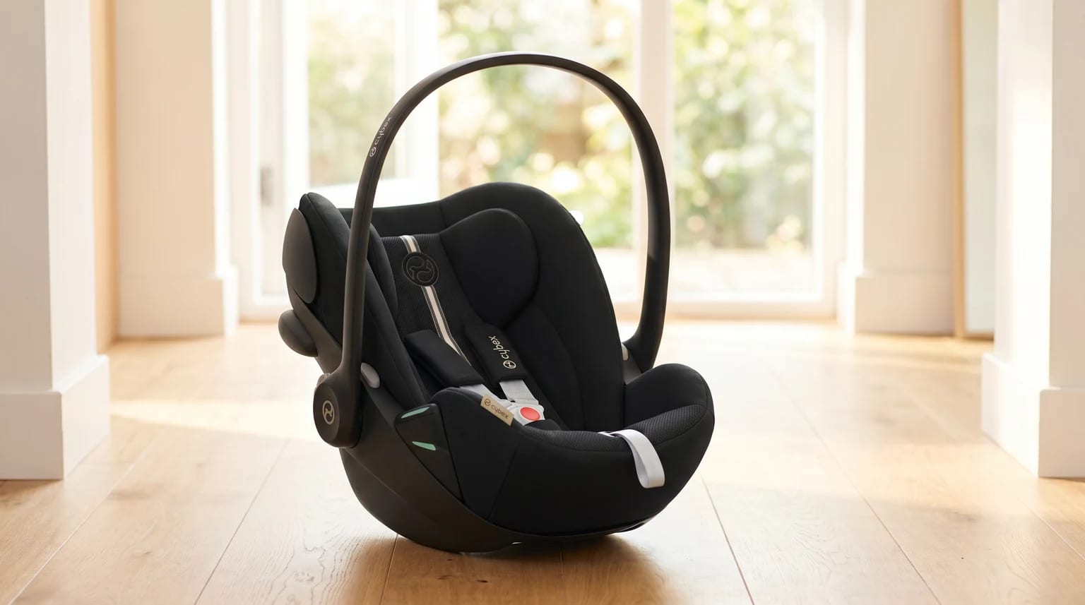 Cadeira auto para bebé Cybex Cloud G preta, pousada num chão de madeira clara numa casa moderna e bem iluminada.