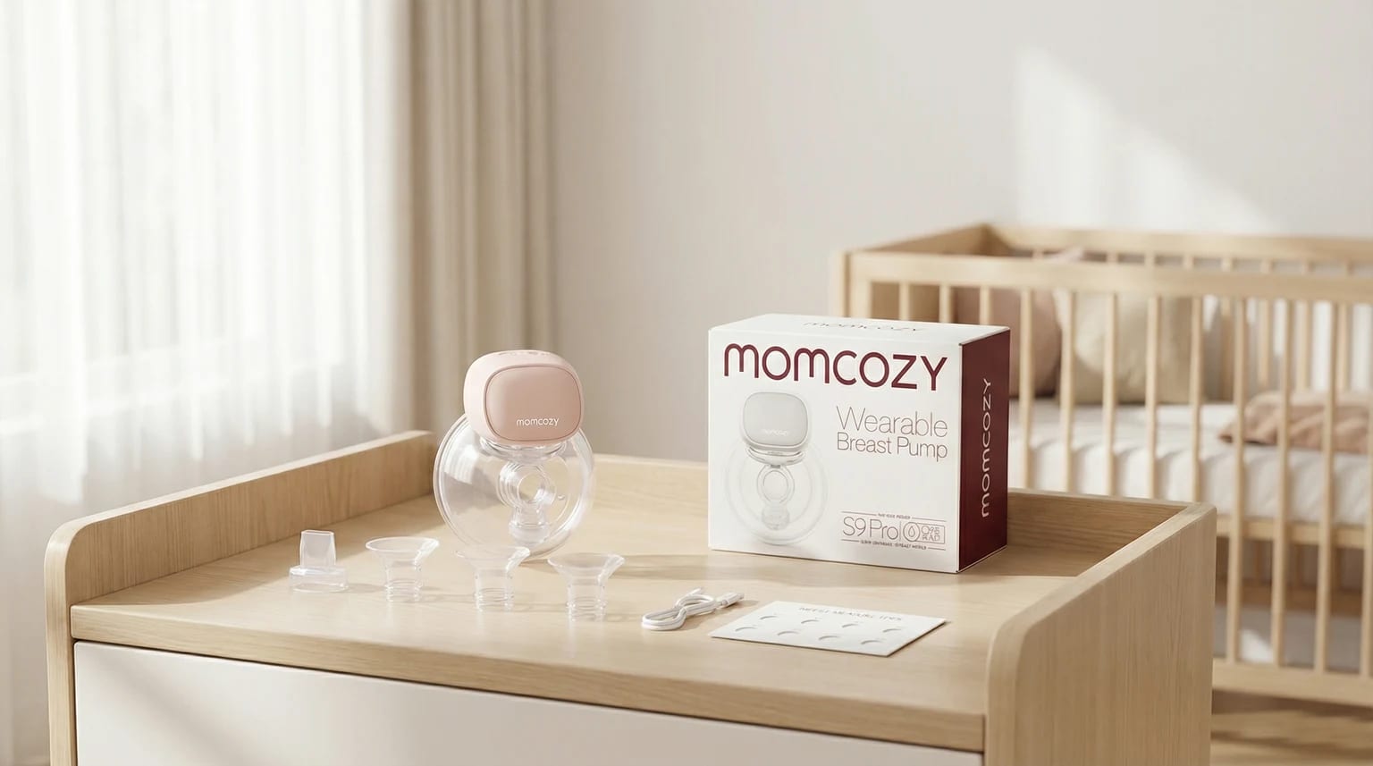 Bomba tira-leite elétrica vestível Momcozy S9 Pro com a caixa e acessórios sobre uma cómoda de madeira clara, num quarto de bebé luminoso.